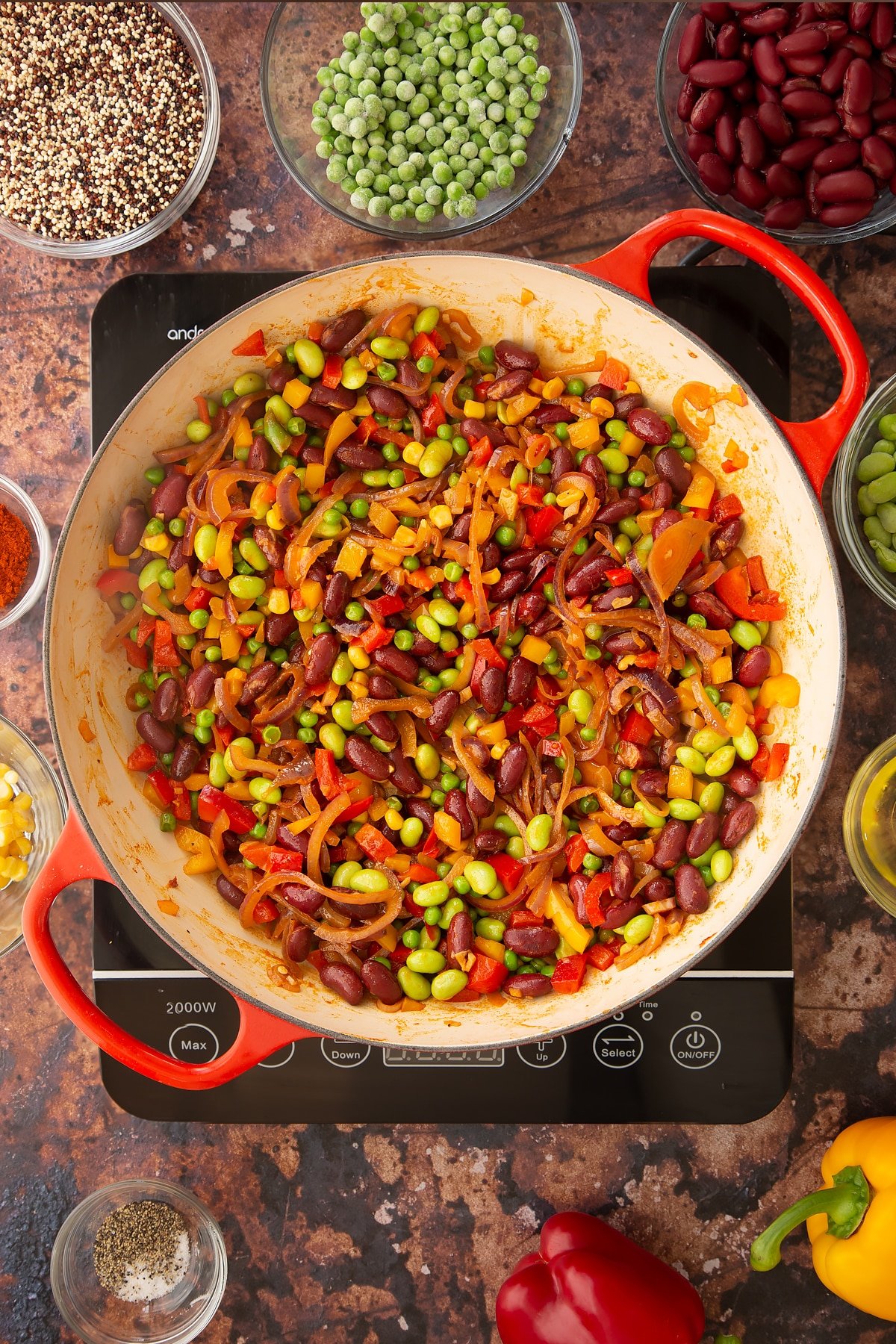 Overhead shot of some of the ingredients required to make the Zesty bean quinoa in a pan on the hob.