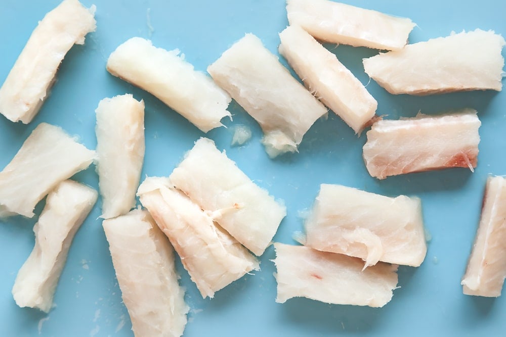 diced cod pieces strewn on a blue background