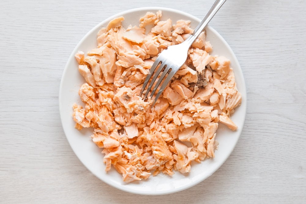 The salmon having been flaked using a fork. This salmon will then be used to create the baked fish cakes without breadcrumbs. 