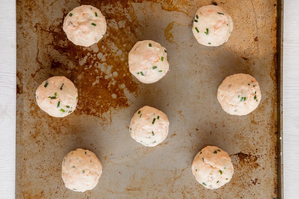 Baked fish cakes without breadcrumbs mixture rolled into balls and laid out on a baking sheet. 