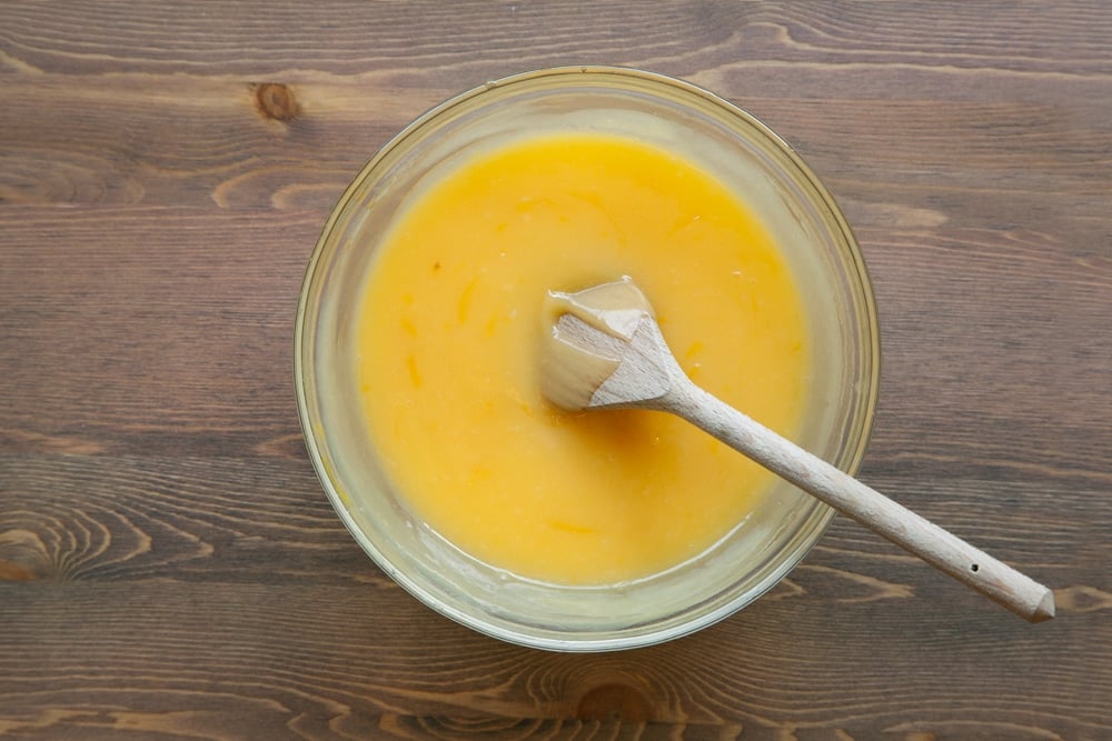 Lemon juice, lemon rind, butter, sugar and eggs, whisked together in a bow over a heat to form lemon curd.