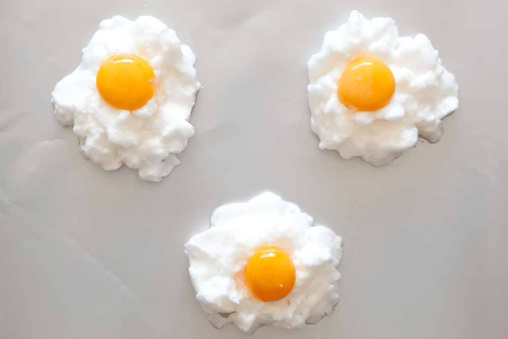 Toppin the eggs in clouds with an egg yolk to create eggs in clouds