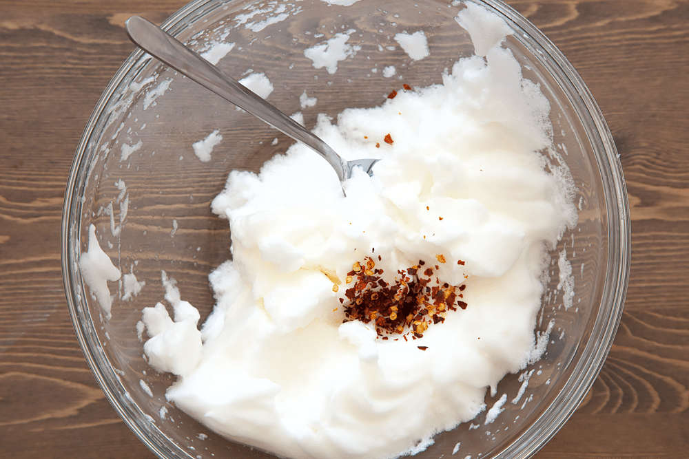 Egg whites in a bowl, with added spices to create spicy eggs in clouds