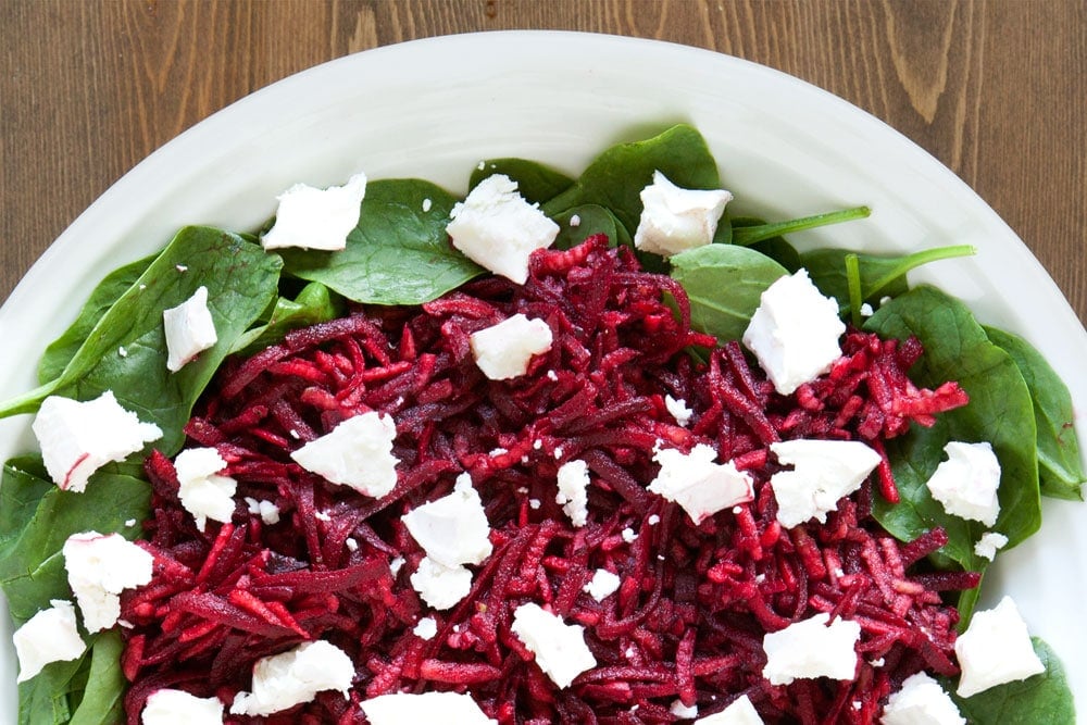 Dressing the apple and beetroot salad with goat's cheese