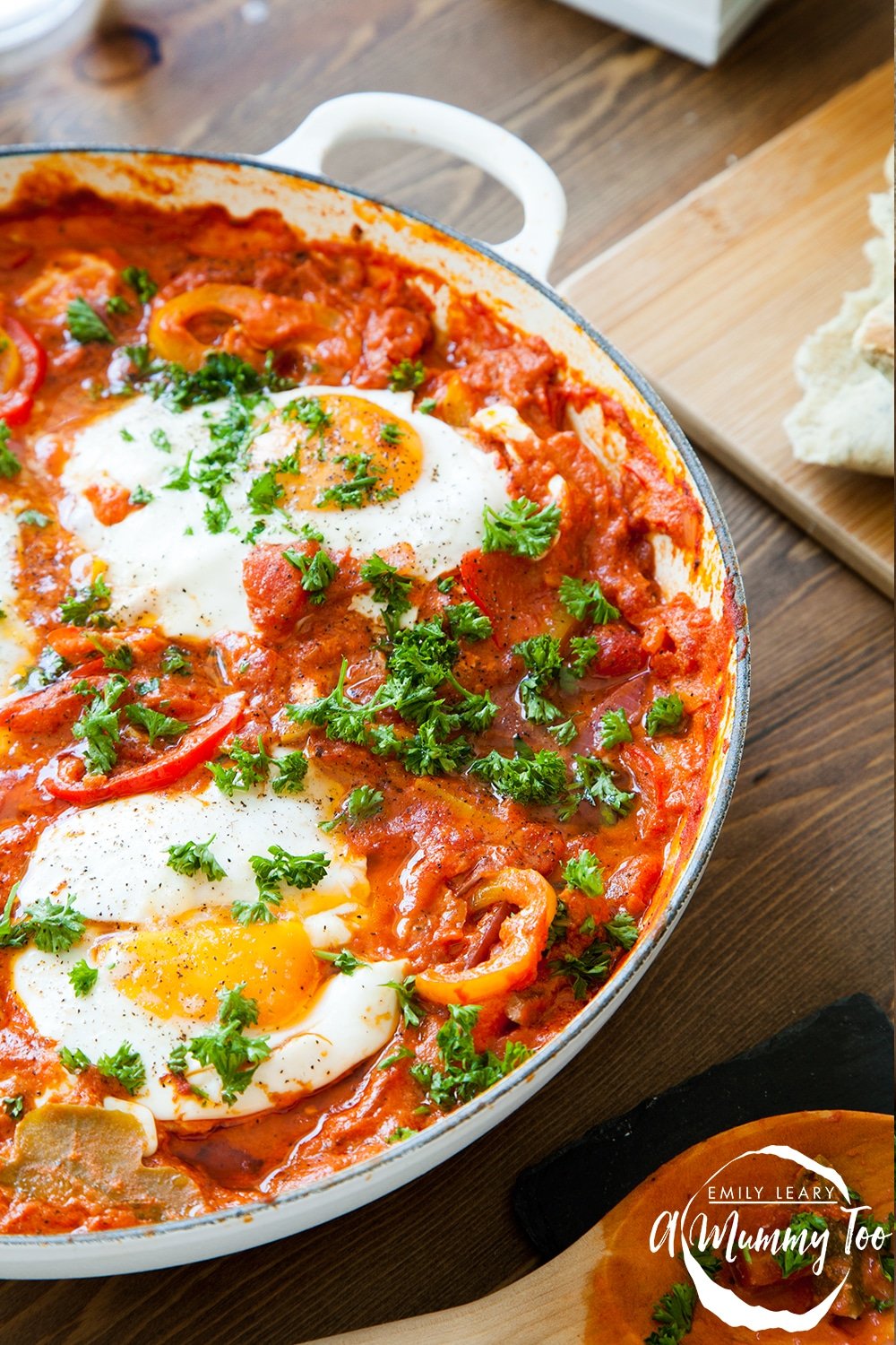 Front view of spicy tomato sauce, cooked egg and chopped parsley in a casserole dish