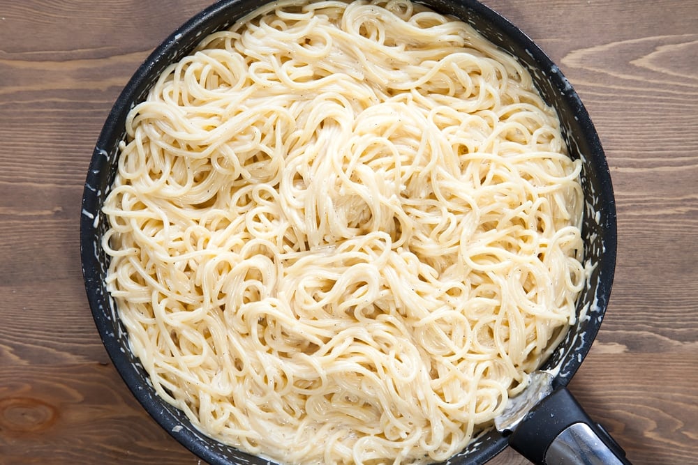 freshly cooked spaghetti coated in a white cream sauce i a frying pan