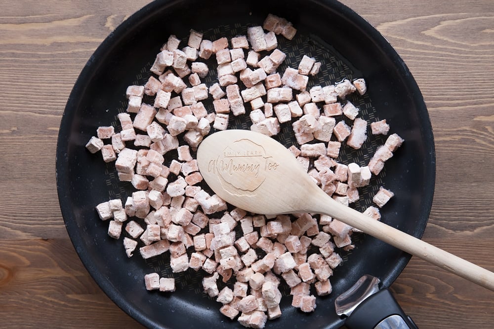 Quorn meat free bacon lardons in a frying pan with a wooden spoon