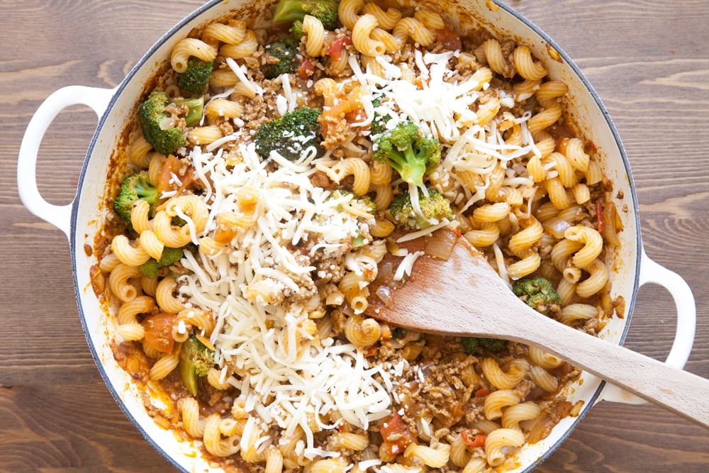 Adding cheese to the lamb keema and pasta 