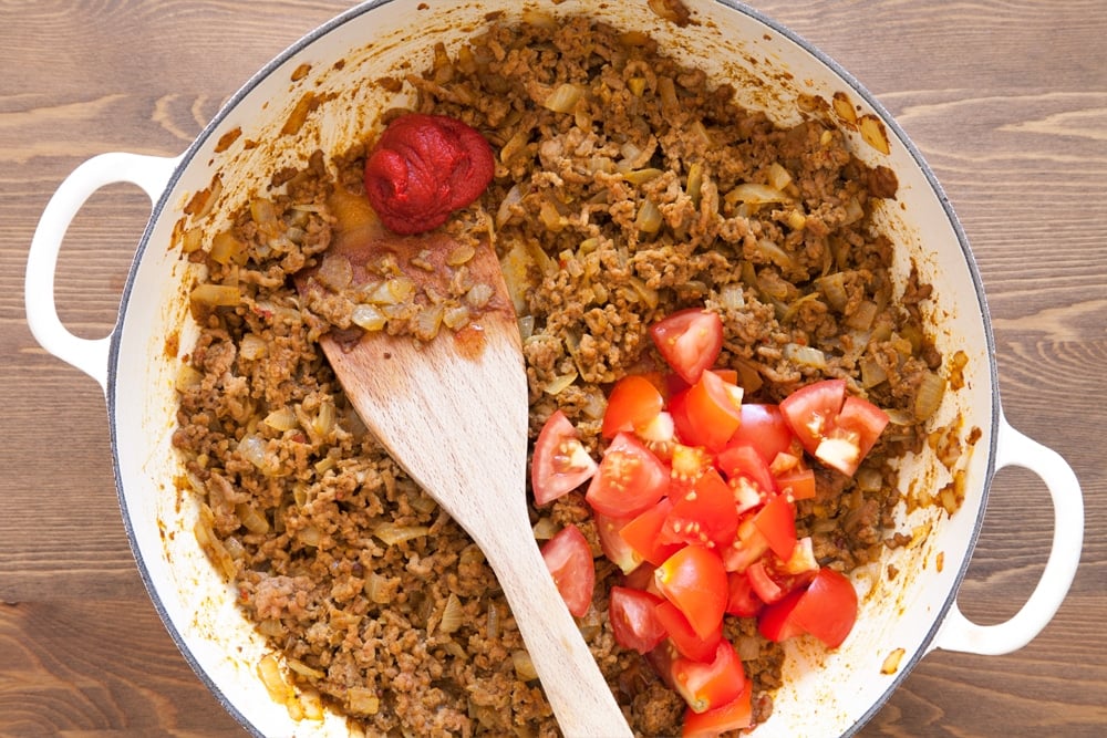 Adding tomatoes and tomato paste to the pan