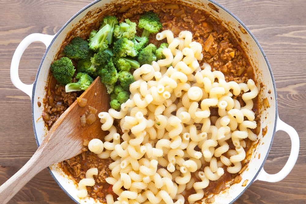 Adding pasta and broccoli to the lamb keema.