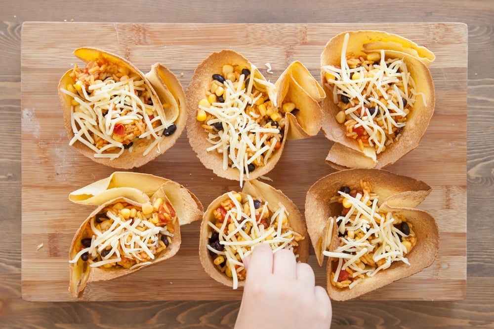 Topping the tacos with grated cheese