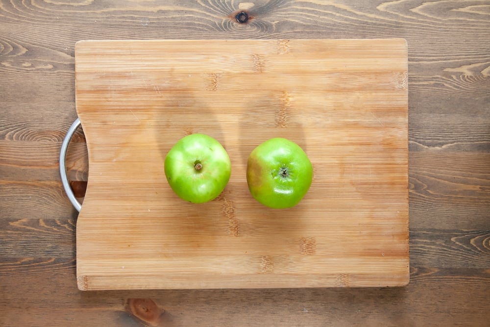 Two bramley apples on a chopping board