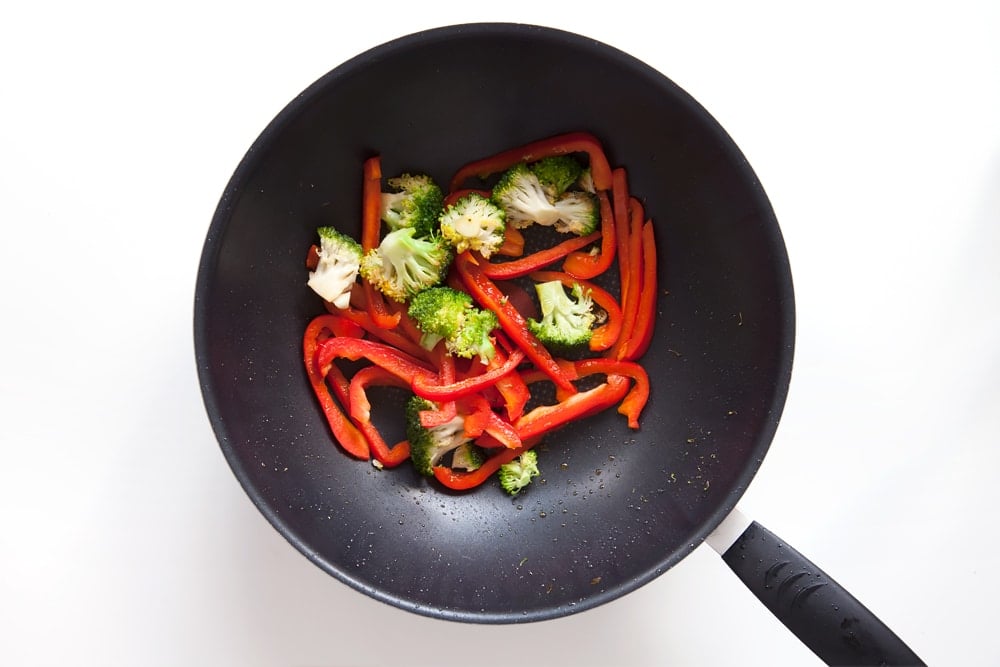 Heating broccoli and red pepper in a wok
