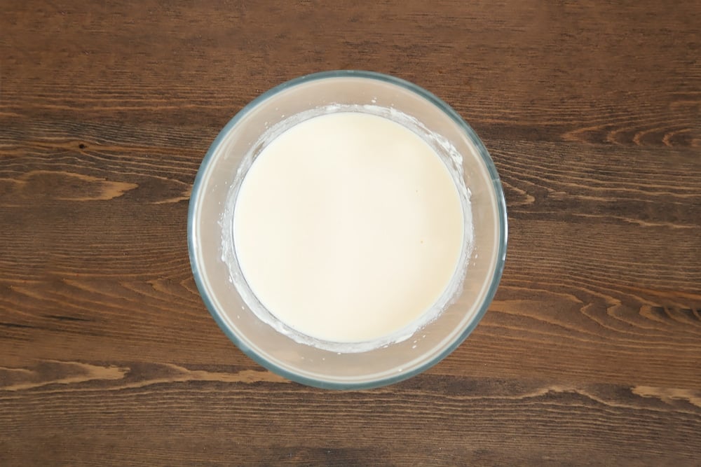 whisked egg and yogurt with added milk in a clear bowl.