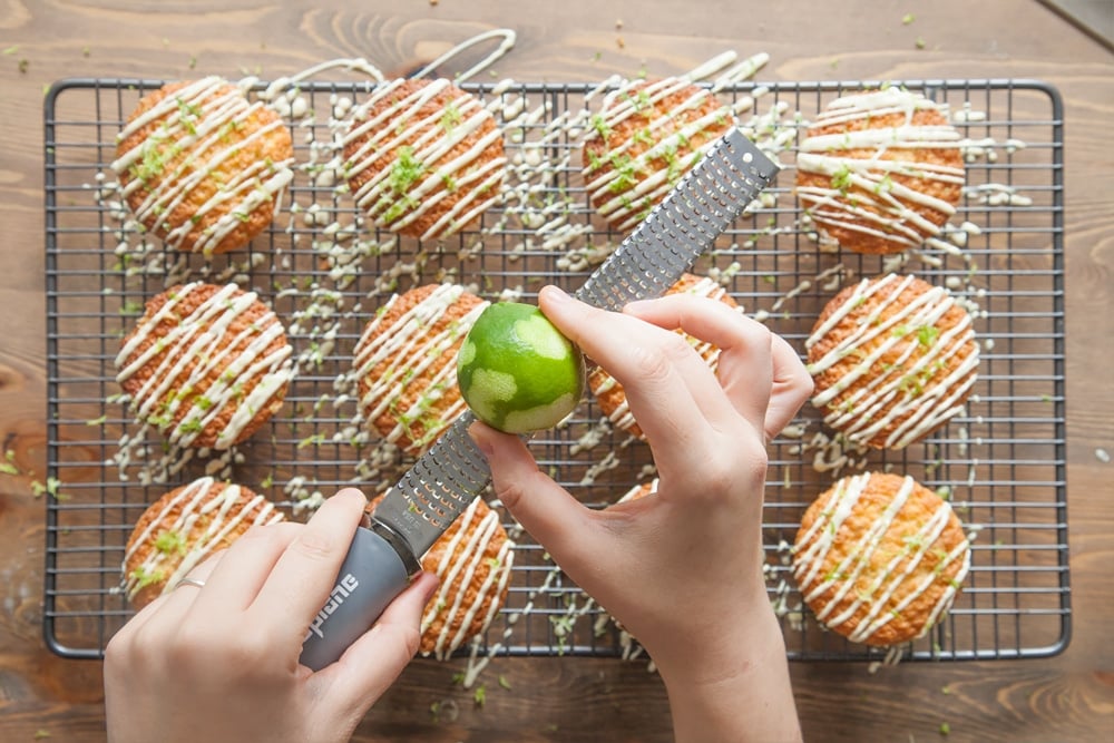 Grating lime zest over the lime and white chocolate muffins
