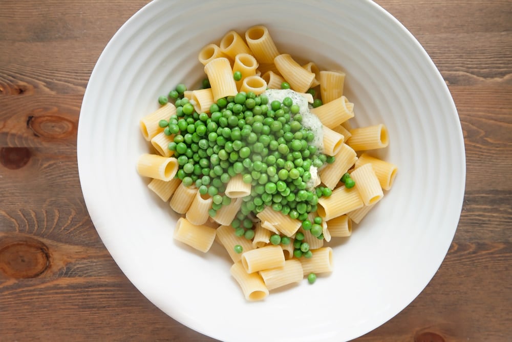 Adding freshly cooked peas to the pasta dish
