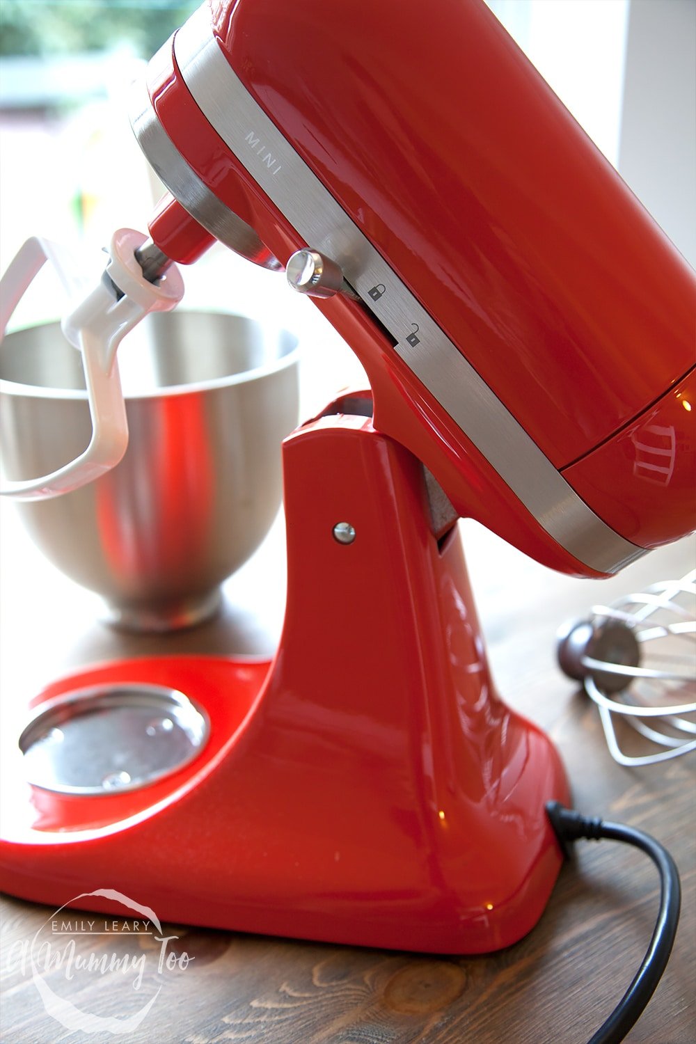 Close up of the side of the KitchenAid mini in red. You can see the MINI engraved onto the side of hte appliance and in the background the bowl which is included with the purchase. 