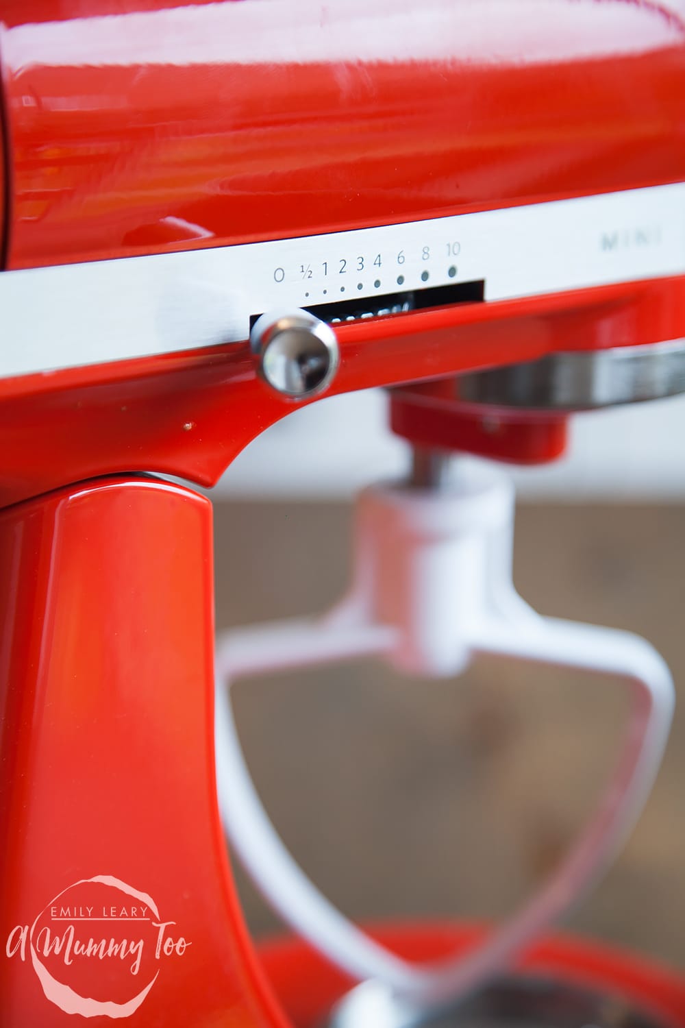 Side view of the red KitchenAid mini. Here you can see the leaver which adjusts the speeds in whcih the main part of the KitchenAid rotates within the bowl.