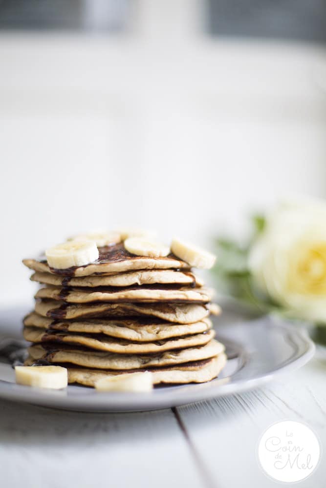 free from banana panckes stacked on a lilac plate topped with slicies of banana.