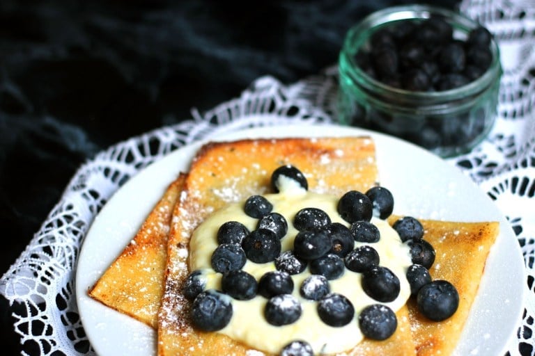 Scandinavian Oven Baked Pancakes by supper in the suburbs laid out on a white plate topped with yogurt and blueberries. 