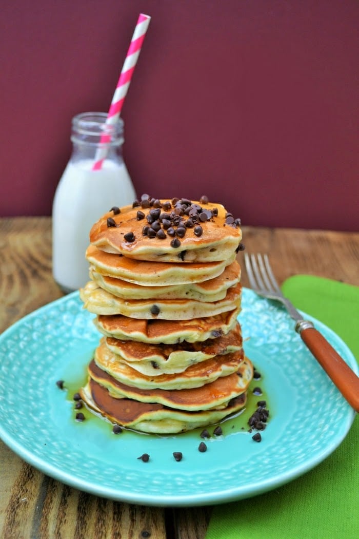chocolate chip and raisin scotch pancakes by tinned tomatoes stacked on a blue plate with a fork on the side