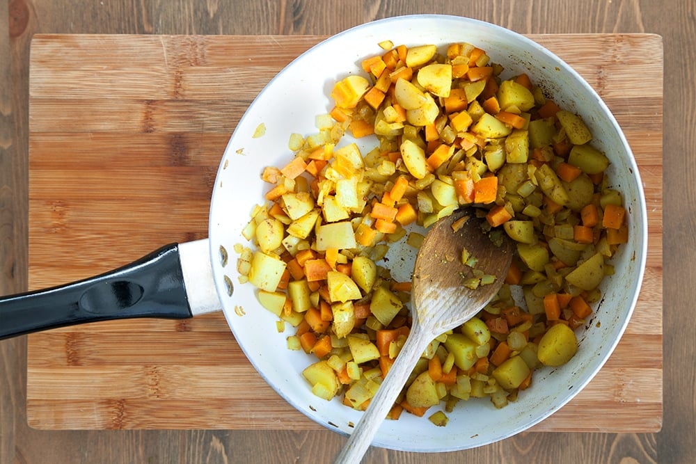 Cooking the chopped vegetables in a frying pan, one of the first steps in creating this tasty carrot and mango curry