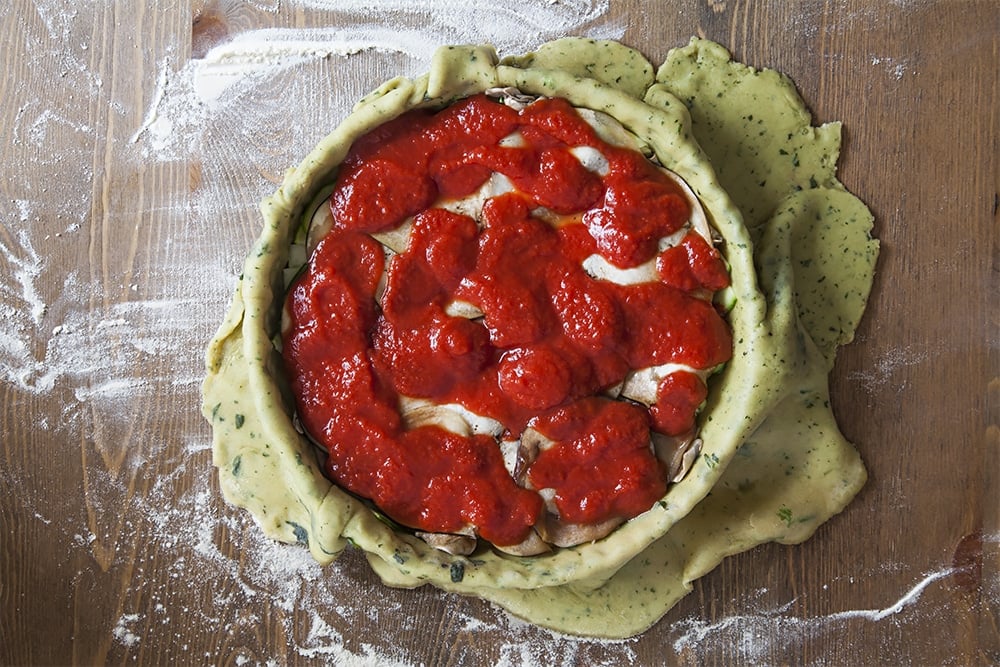 Assembling the layered vegetable pie with basil infused pastry - top with half the passata