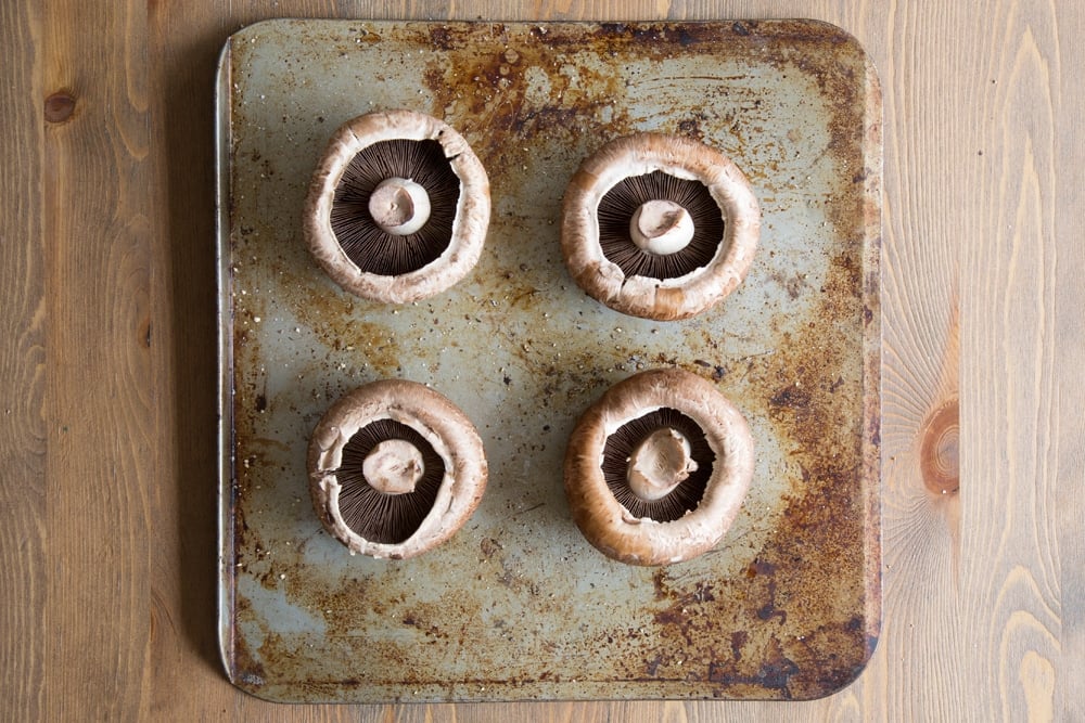 Preparing the portobello mushrooms by cutting off the stalks