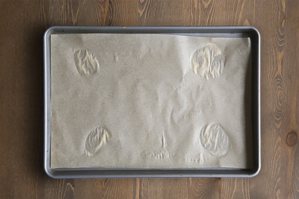 a baking tray lined with greaseproof paper on a wooden background