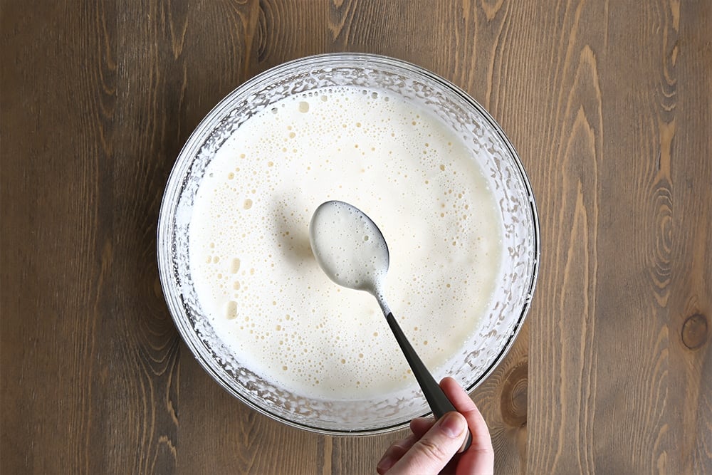 sugar, eggs and vanilla extract whisked together to create a fluffy liquid in a clear bowl