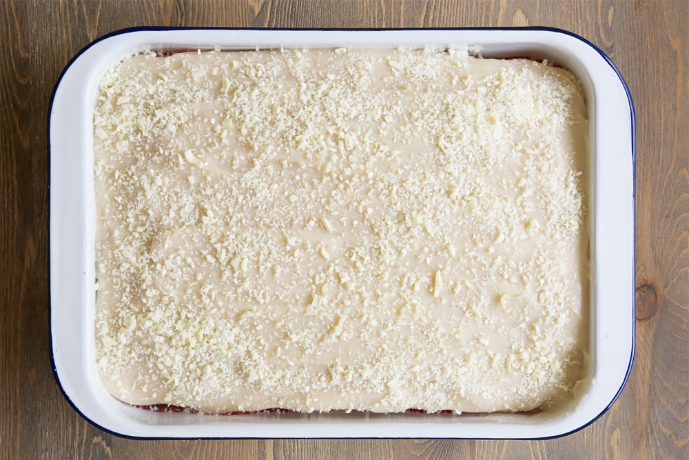 A white metal dish topped with a vanilla sponge layer with a white sauce covered the top with a sprinkling of white chocolate shavings.