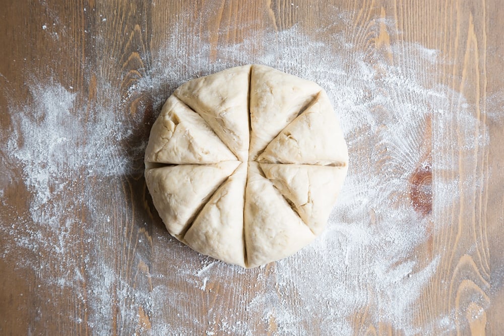 Tortilla dough cut into eight triangles, ready to be rolled into balls