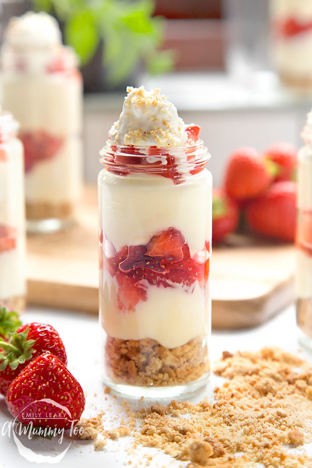 Strawberry no-bake cheesecake shots in a glass jar topped with cream