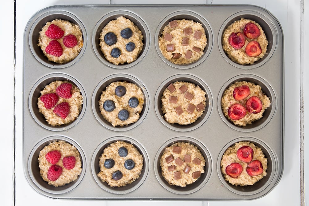 The yogurty breakfast muffins are ready to bake! Shown here topped with raspberries, blueberries and chocolate chips