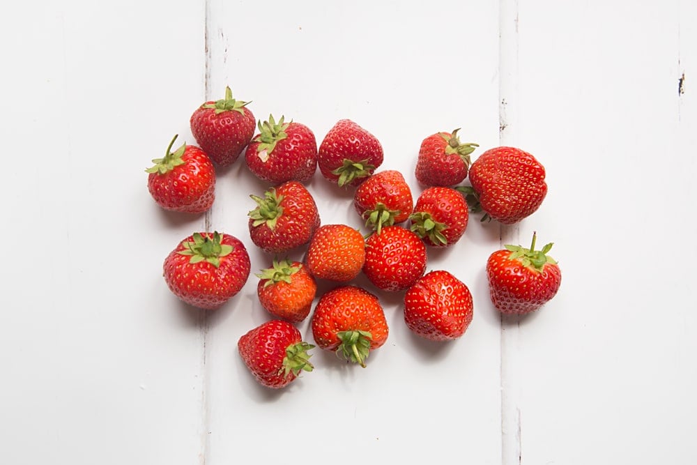 Fresh strawberries with stalks on a white background