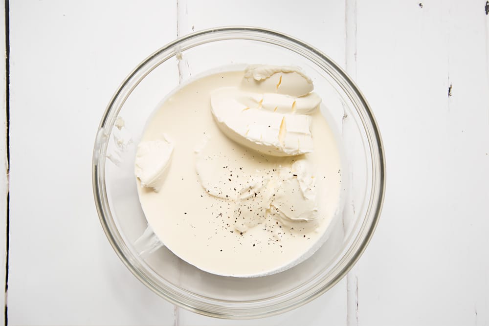 cream cheese, cream and vanilla in a large clear bowl on a white background