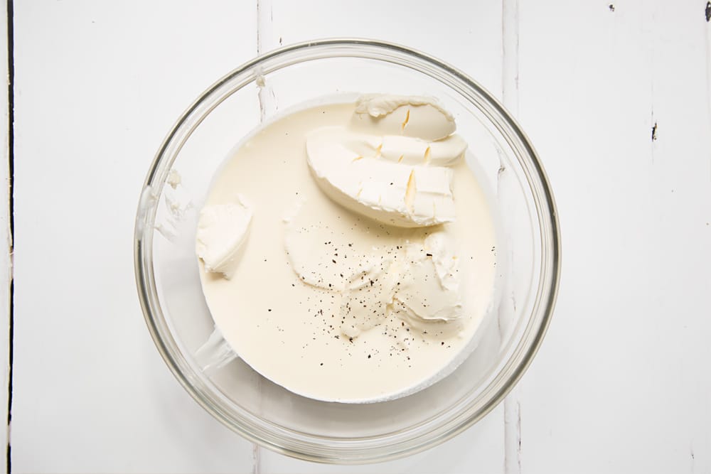 cream cheese, cream and vanilla in a large clear bowl on a white background