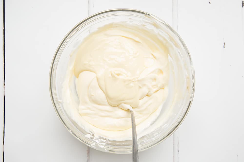 Melted white chocolate in a clear mixing bowl on a white background