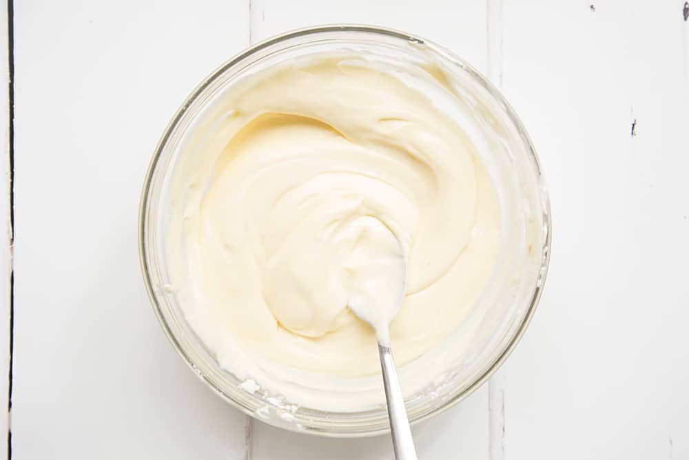 Melted white chocolate in a clear mixing bowl on a white background