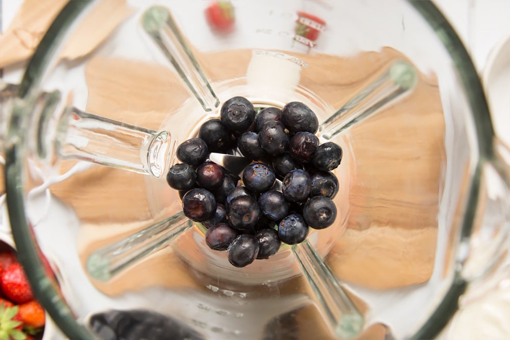 Blueberries shown inside a blender, part of this quick and simple fruit and yogurt lollies recipe