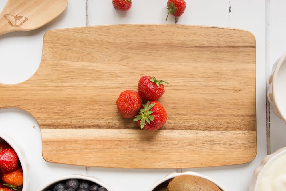 Strawberries, one of the main ingredients in this fruit yogurt lolly, shown on a chopping board