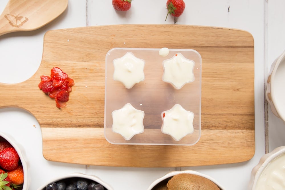 The blueberry and yogurt mix is spooned into the ice lolly moulds carefully