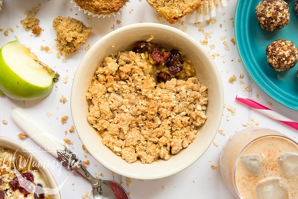 Freshly warmed apple cherry granola crumble, shown alongside breakfast bran muffins, date granola energy balls, spiced granola smoothie and apples