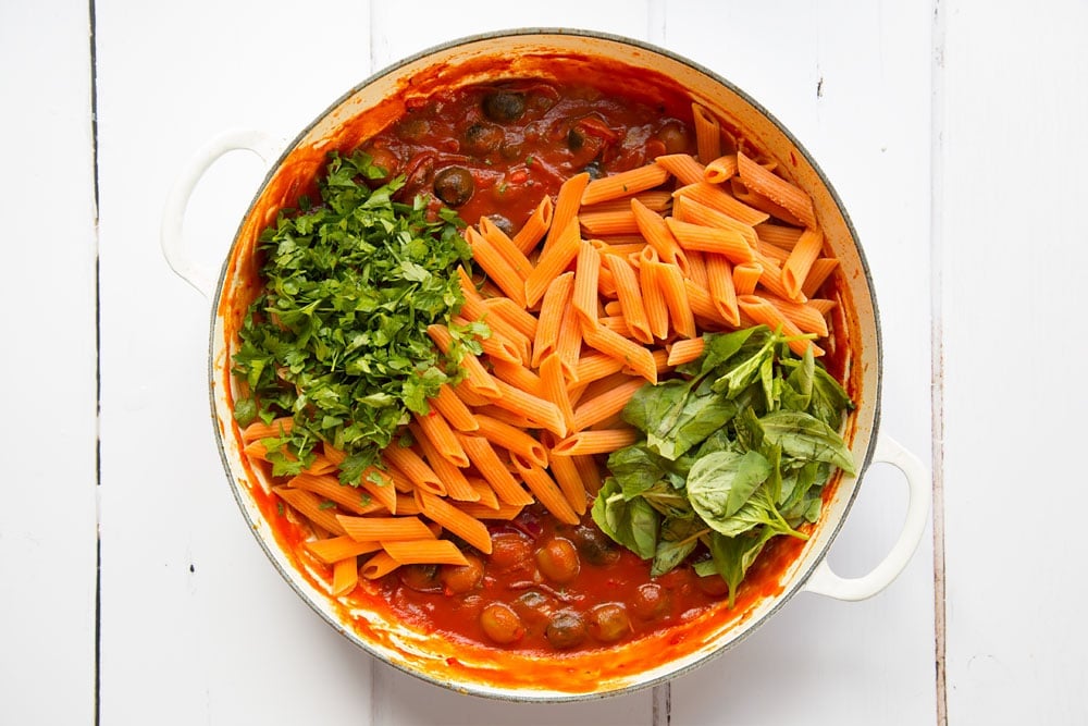 The pasta, parsley and basil are added to the pan