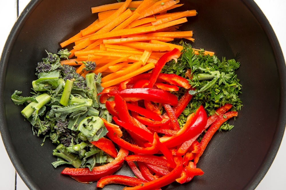 Preparing the stir fry in a pan, starting with chopped vegetables