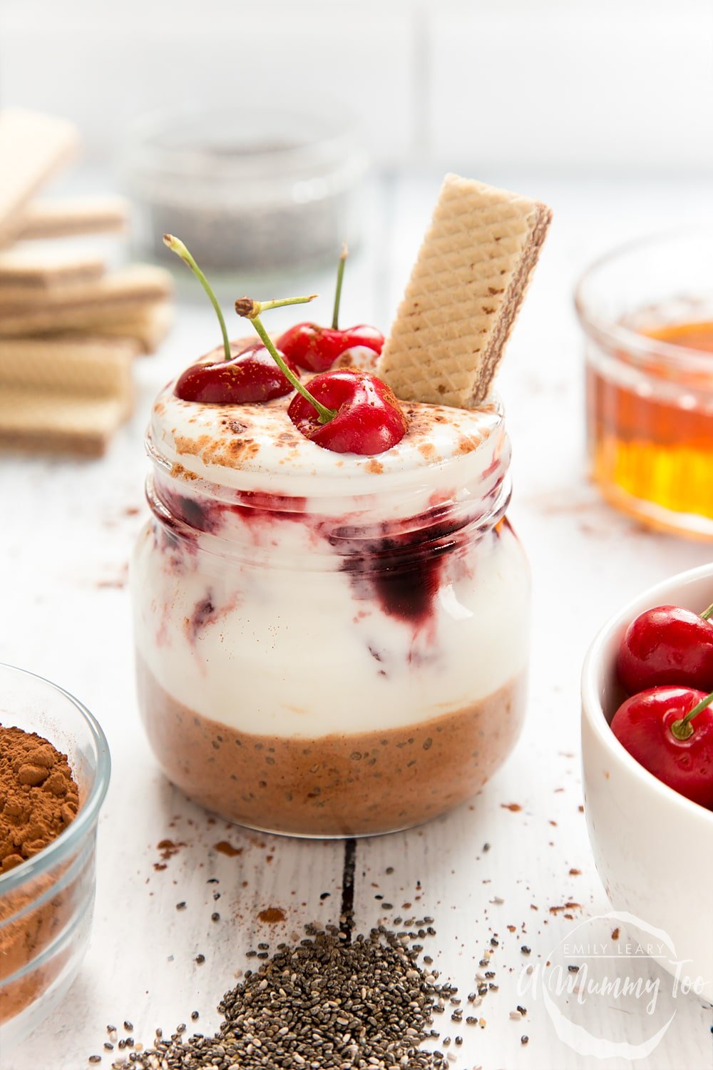 This black forest breakfast jar features layers of yogurt and cherry conserve, topped with cherries and a wafer