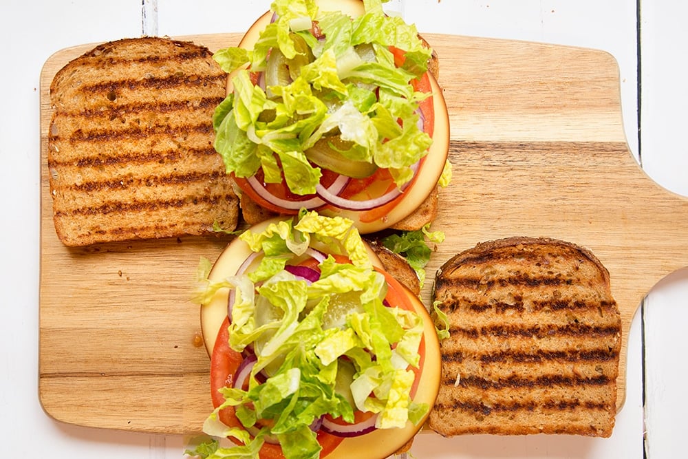 Gherkins and lettuce are added to the final layer of the sandwich