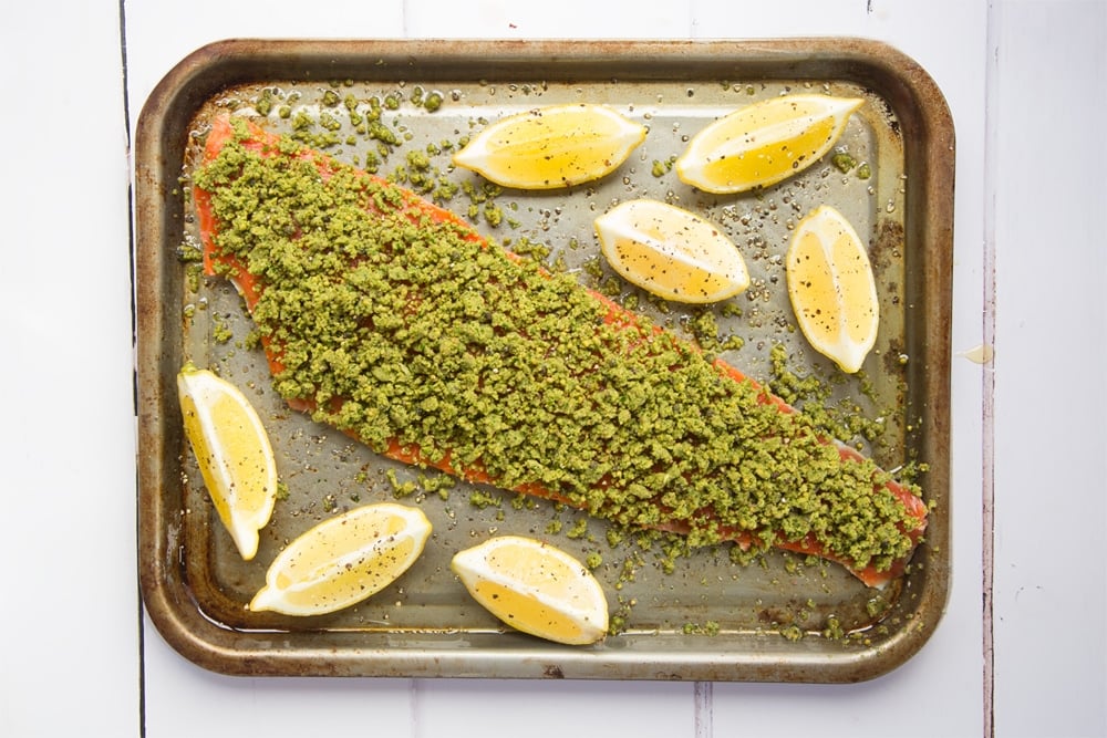 Lemon wedges are added to the Alaska salmon fillet ready to bake