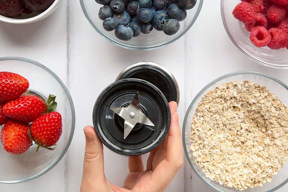 Showing the blender in action, blending the fresh fruit with ice