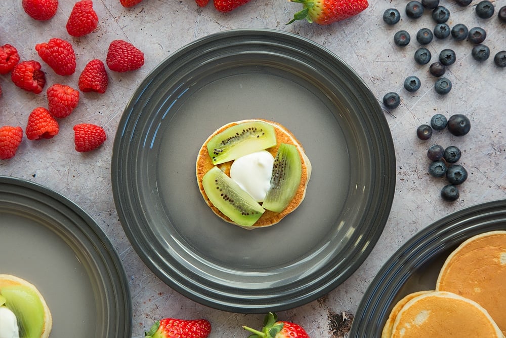 Start building your fruity pancake stack with a pancake topped with kiwi and yogurt